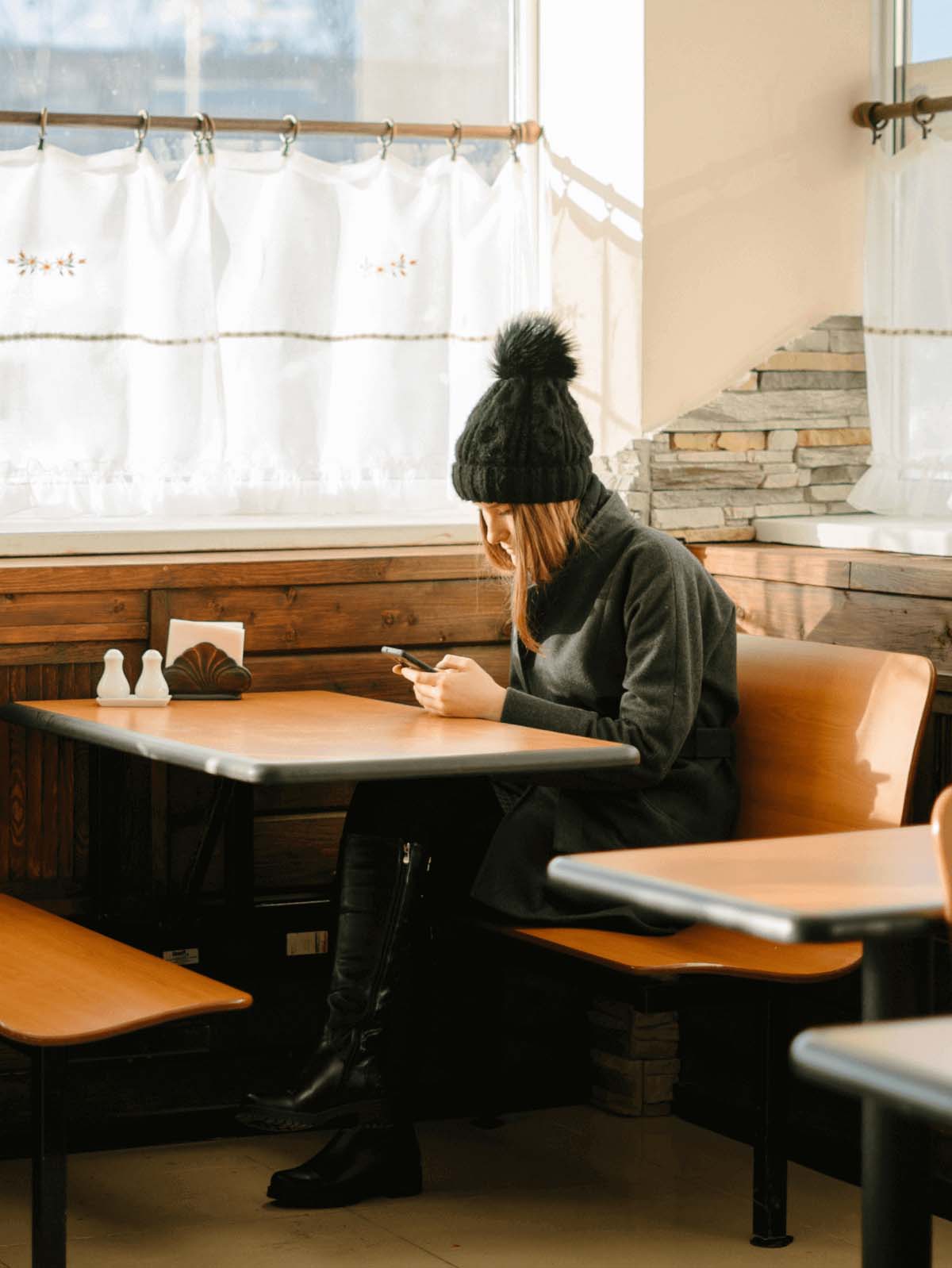 A woman sitting at a café looking at her phone.