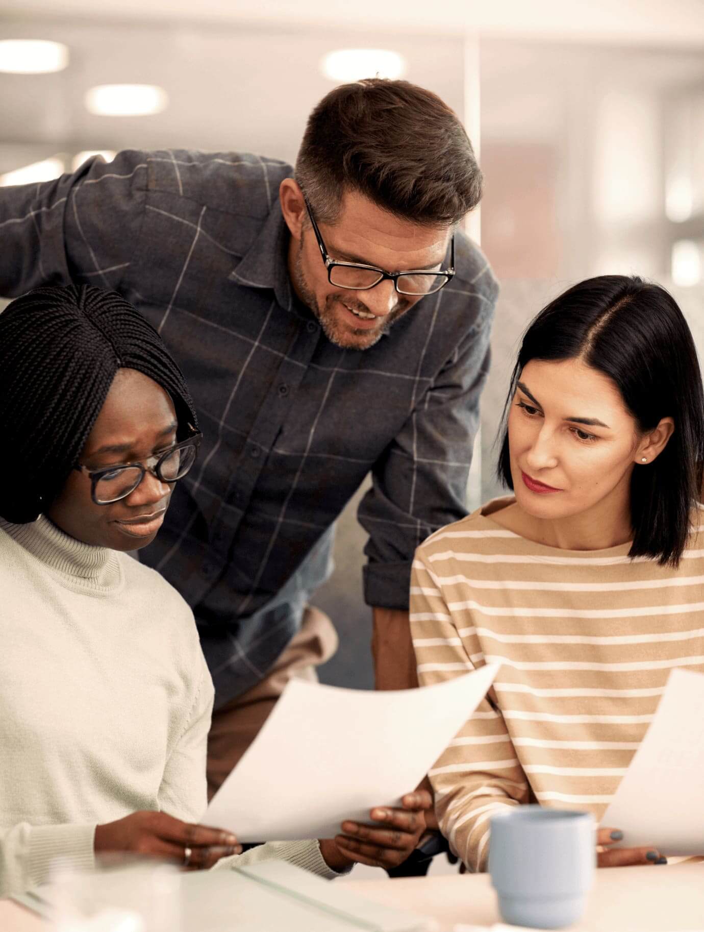 Three middle aged people having a chat in an office environment.