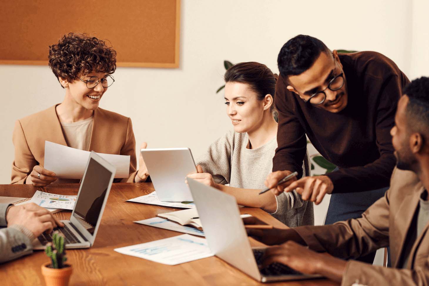 A group of people by a table in an office interacting with each other.