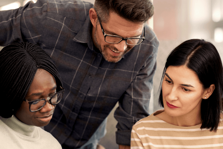 Three middle aged people having a chat in an office environment.